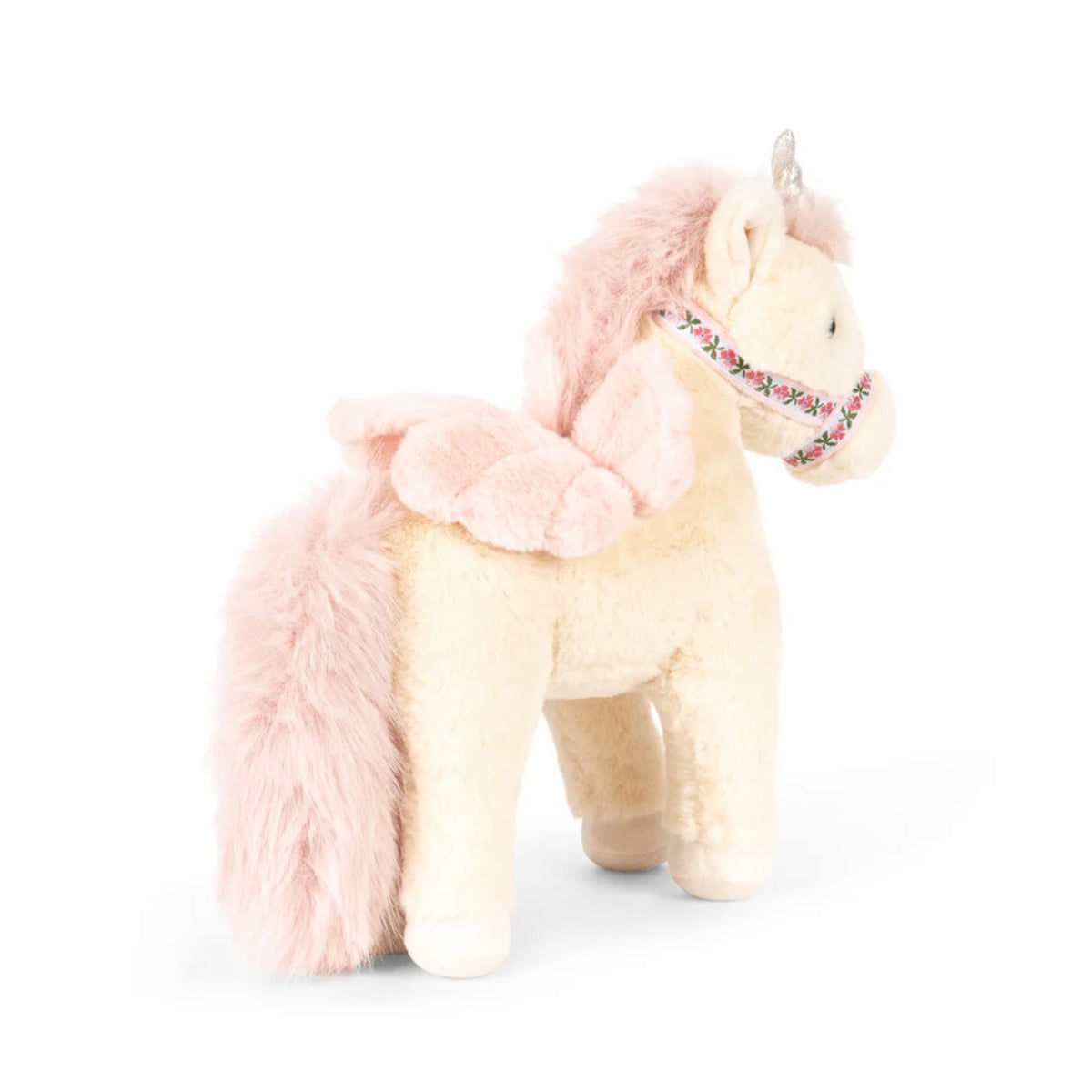 A plush unicorn toy with a cream-colored body, fluffy pink mane and tail, and a decorative pink and green bridle, set against a plain white background.