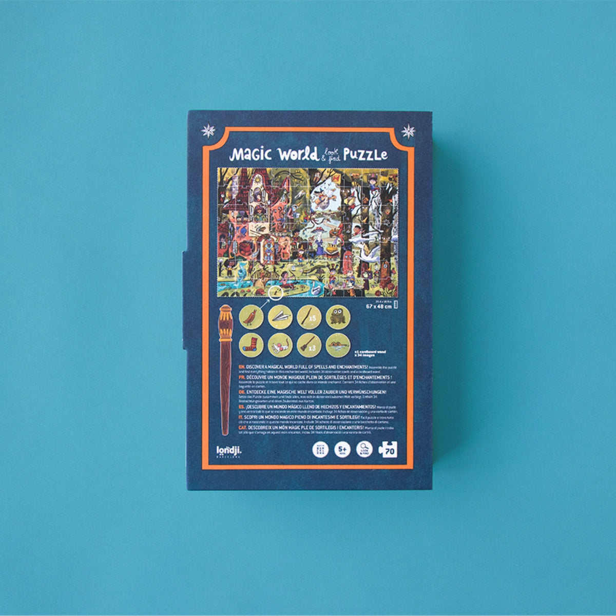 A boxed jigsaw puzzle package labeled 'Magic World Look & Find Puzzle' lays face down on a solid teal background. The box is dark blue with an orange border and a colorful illustrated puzzle scene on the front, plus small circular icons and text near the bottom.