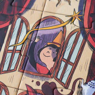 A close-up of a jigsaw puzzle showing a whimsical child with a pointed hat and star wand, set against a warm beige background with red, purple, and blue details.