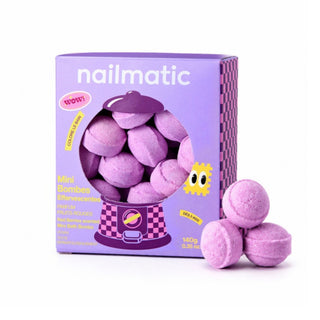 A purple box of nailmatic mini bath bombs with three loose bath bombs placed in front on a clean white background.