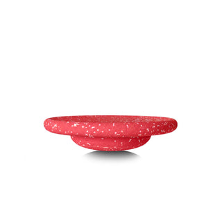 A red speckled round balancing board shown from a side profile view on a white background.