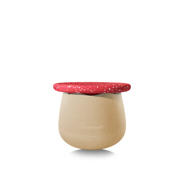 A modern, rounded stool with a textured beige body and a contrasting vivid red speckled with small white dots, shown on a clean white background. Stool resembles a toadstool.