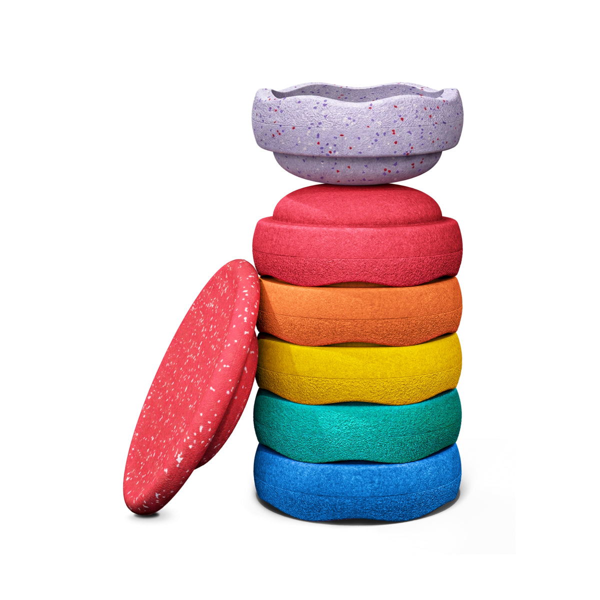 A set of six textured, Original Stapelstein pieces in red, orange, yellow, green, and blue, with a matching speckled lavender piece resting on top, shown on a solid white background. A red speckled wobble board is leant up against the stack.